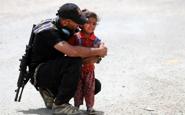 An Iraqi soldier helps a displaced girl after leaving their homes west of Mosul on May 26, 2017, as government forces continue their offensive to retake the city of Mosul from Islamic State (IS) group fighters. (AFP/Karim Sahib)