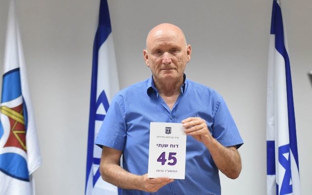 IDF Ombudsman Yitzhak Brick poses with a copy of his annual report on May 28, 2017. (Defense Ministry)