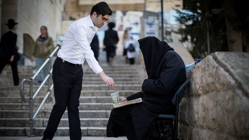 An ultra-Orthodox man gives change to a beggar alongside the staircase leading from the Jewish Quarter in Jerusalem's Old City to the Western Wall on February 26, 2017. (Hadas Parush/Flash90)