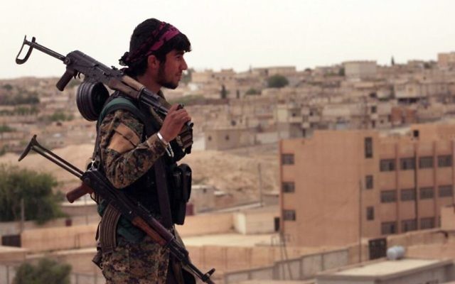 This April 30, 2017 photo shows a fighter from the US-backed SDF carrying weapons as he looks toward the northern town of Tabqa, Syria. (Syrian Democratic Forces, via AP)
