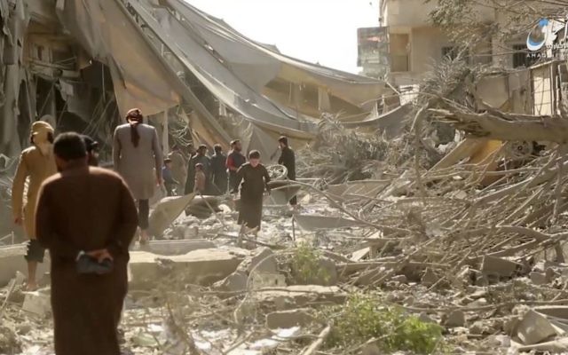 This undated frame grab from video posted online Monday, May 29, 2017, by the Aamaq News Agency, a media arm of the Islamic State group, shows people inspecting damage from airstrikes and artillery shelling in the northern Syrian city of Raqqa, the de facto capital of the IS. (Aamaq News Agency via AP)