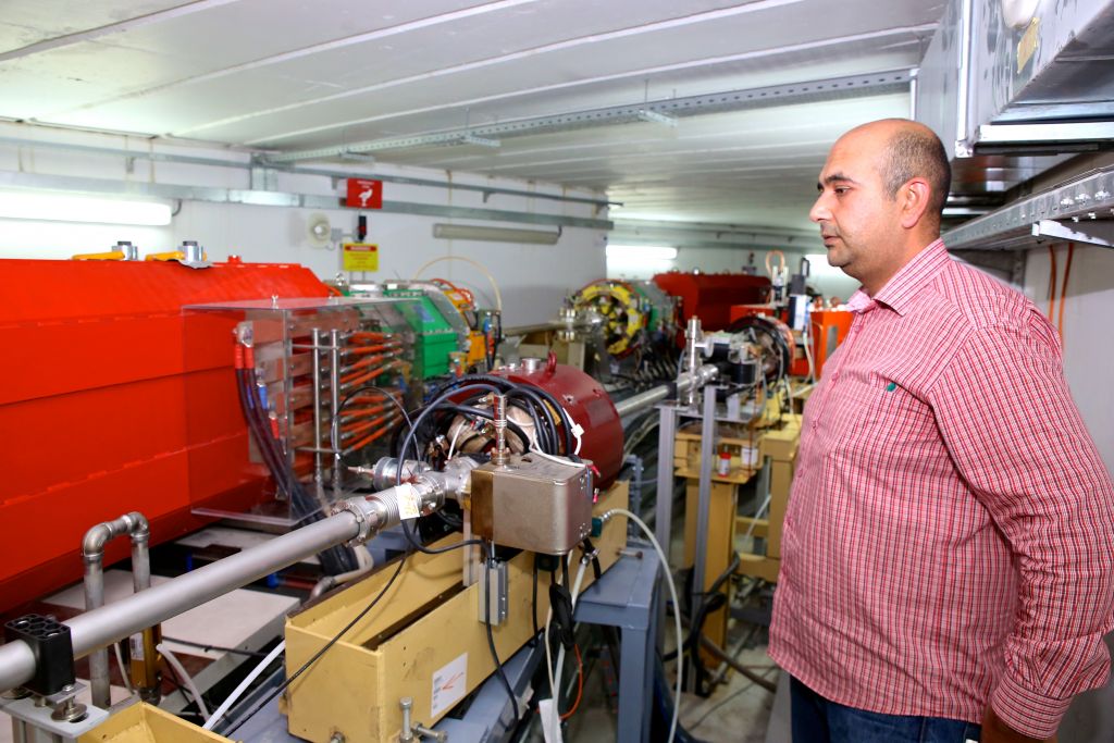 An employee from SESAME stands next to the particle accelerator in Allan, Jordan. (Sharing Knowledge Foundation) 
