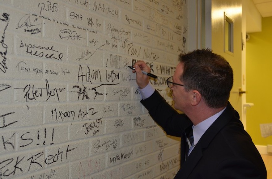 Joshua Malina signs his name on the wall of Sixth and I, a historic Washington, DC, synagogue, at a Shavuot event last year. The synagogue's Shavuot event this year features Jeffrey Goldberg, editor of the Atlantic, and Imam Abdullah Antepli. (Courtesy of Sixth and I/via JTA)