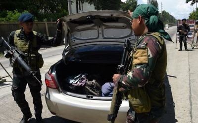 Philippine policemen check the car boot of a resident fleeing from Marawi city, where gunmen who had declared allegiance to the Islamic State group staged a rampage, May 24, 2017. / AFP PHOTO / TED ALJIBE