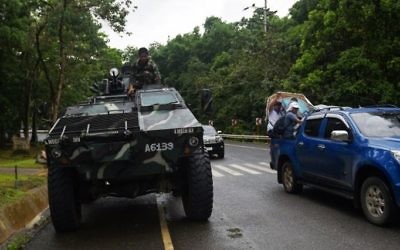 A Philippine soldier sits on an Armoured Personnel Carrier (APC) while residents fleeing from Marawi city drive past on a highway going to Marawi, in Balo-i town, on the southern island of Mindanao, May 24, 2017. / AFP PHOTO / TED ALJIBE