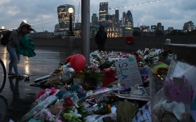 A woman looks at flowers laid at Potters Fields Park in London on June 5, 2017, after a vigil to commemorate the victims of the terror attack on London Bridge and at Borough Market that killed seven people on June 3. (AFP PHOTO / Chris J Ratcliffe)