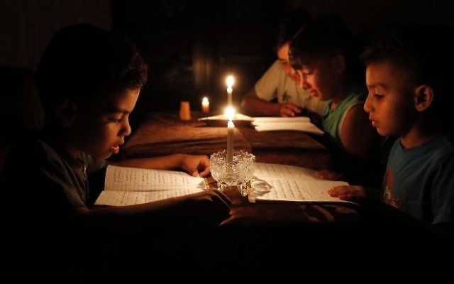 A picture taken on June 13, 2017, shows Palestinian children at home reading books by candle light due to electricity shortages in Gaza City. (AFP/ THOMAS COEX)