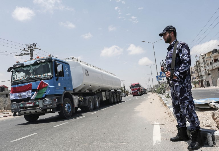 Palestinian security forces stand guard as Egyptian trucks carrying fuel drive down a street after entering the southern Gaza Strip from Egypt through the Rafah border crossing on June 21, 2017. (AFP Photo/Said Khatib)
