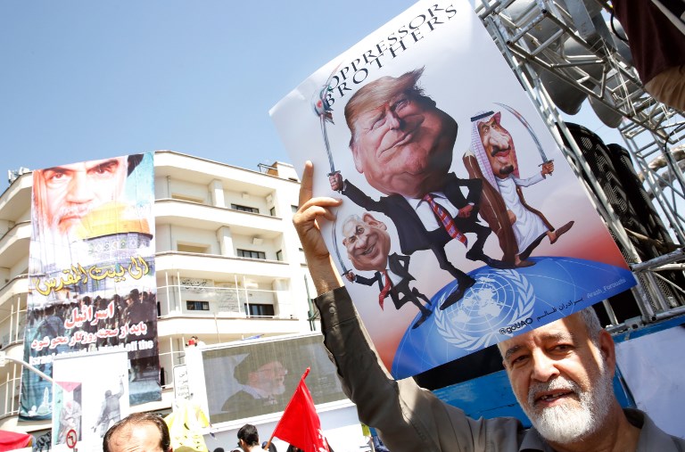 An Iranian man holds a poster bearing images of Israeli Prime Minister Benjamin Netanyahu, US President Donald Trump and Saudi King Salam during a parade marking al-Quds (Jerusalem) day in Tehran on June 23, 2017. (AFP PHOTO / STRINGER)
