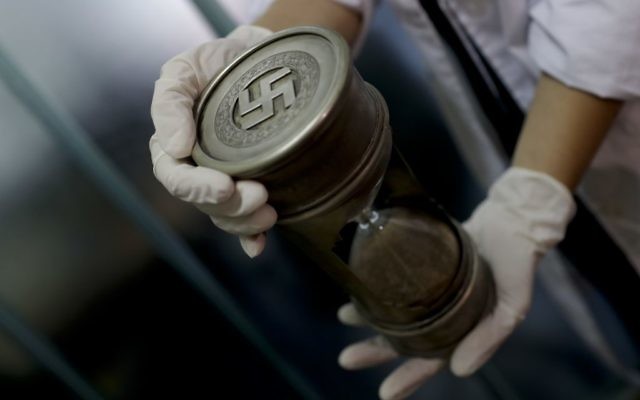 A member of the federal police holds an hourglass with Nazi markings at the Interpol headquarters in Buenos Aires, Argentina, June 16, 2017. (AP/Natacha Pisarenko) 