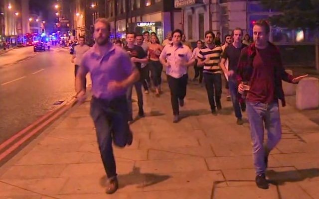 In this image taken from video footage, people run from the scene of attack, alongside a man strolling holding a pint of beer, right, in London on June 3, 2017. (Sky News via AP)