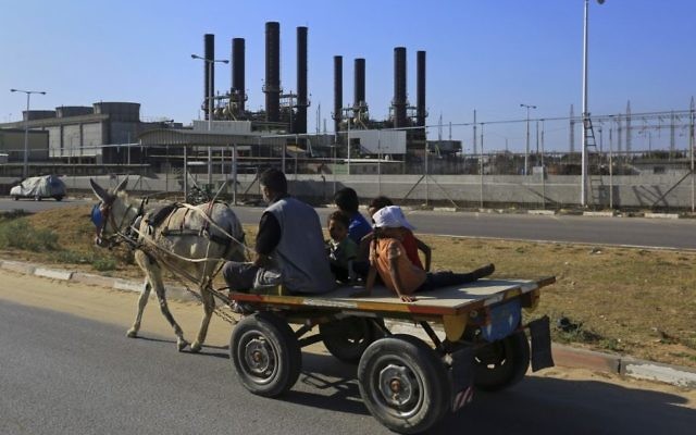 In this June 4, 2017, photo, a father and his children ride their donkey cart past the idled Gaza power plant at Nusseirat, in the central Gaza Strip (AP Photo/Adel Hana)
