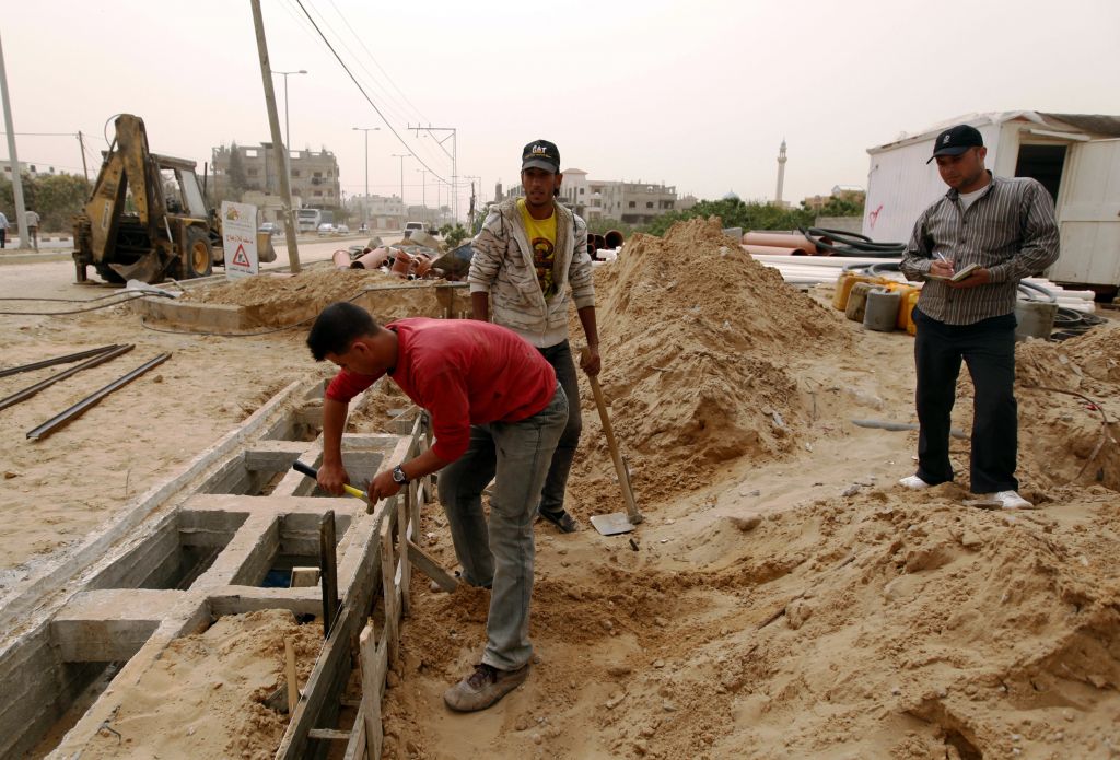 In this April 8, 2013 photo, Palestinians work on a Qatar-funded road in Gaza City. (AP Photo/ Hatem Moussa)