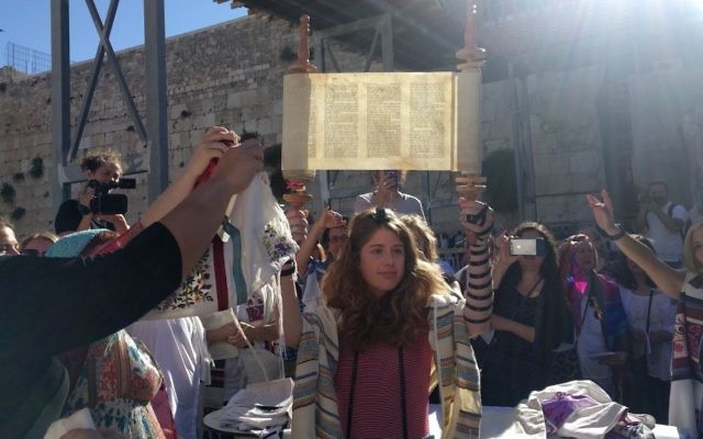 Illustrative: A young member of Women of the Wall holds up the miniature Torah scroll during the monthly Rosh Hodesh service on June 25, 2017, in the women's section of the Western Wall plaza. (Melanie Lidman/Times of Israel)