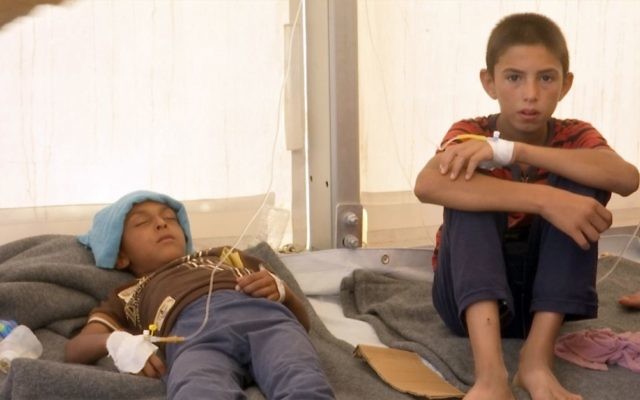 In this screen grab from video, a boy and his brother receive treatment for suspected food poisoning at a medical tent in the Hassan Sham U2 camp for displaced peopleeast of Mosul, Iraq, June 13, 2017. (AP/Balint Szlanko)