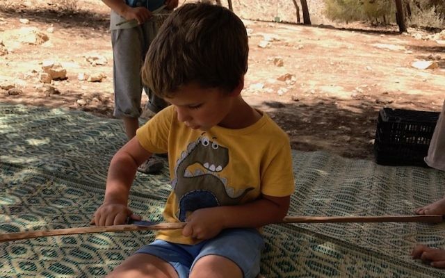 A boy carving a stick with a switchblade in Mitzpe Ramon, Israel, June 13, 2017. (Andrew Tobin) 