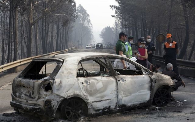 Police investigators stand by a burnt car on the road between Castanheira de Pera and Figueiro dos Vinhos, central Portugal, June 18 2017. (AP/Armando Franca) 