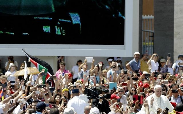 Pope Francis, bottom right, is driven through the crowd as his image is projected on a giant screen, in St. Peter's Square, at the Vatican, Sunday, June 4, 2017. (AP Photo/Gregorio Borgia)