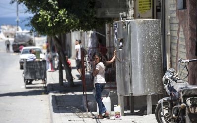 A Palestinian girl fills a jerrycan with water during a heatwave at al-Shati refugee camp in Gaza City on July 2, 2017. (AFP Photo/Mahmud Hams)