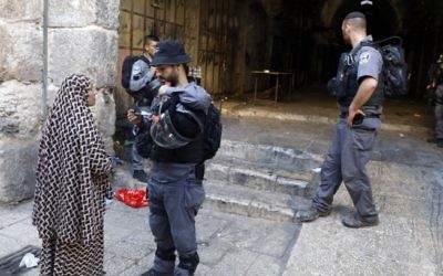 An Israeli border policeman inspects the identification card of a Palestinian woman in Jerusalem's Old City, on July 16, 2017. (Menahem Kahana/AFP)