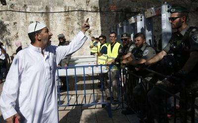 A Palestinian man argues with Israeli border policemen standing guard near newly-installed metal detectors at a main entrance to the Al-Aqsa mosque compound in Jerusalem's Old City, July 16, 2017, after security forces reopened the ultra-sensitive site. (AFP PHOTO / AHMAD GHARABLI)