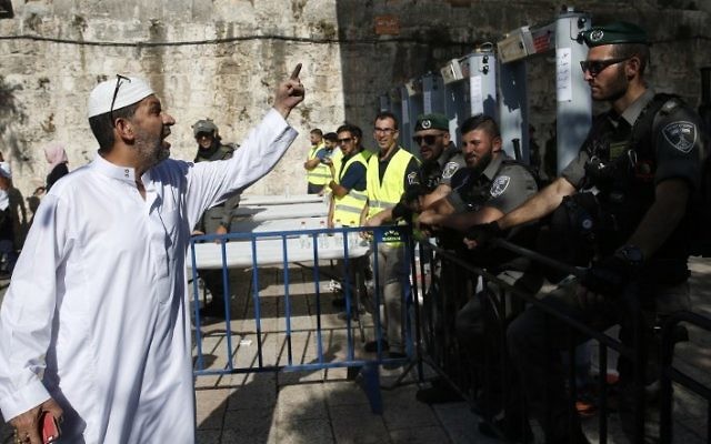 A Palestinian man argues with Israeli border policemen standing guard near newly installed metal detectors at a main entrance to the Temple Mount, on July 16, 2017. (AFP/Ahmad Gharabli)