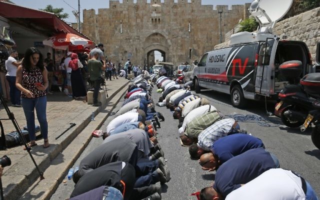 Muslim worshipers who refuse to enter the Temple Mount due to newly implemented security measures by Israeli authorities pray outside the Lions Gate in Jerusalem's Old City on July 17, 2017. (AFP/AHMAD GHARABLI)