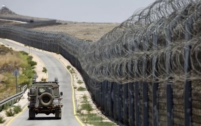 An IDF vehicle drives along the road parallel to the border fence separating the Israeli and Syrian regions of the Golan Heights, July 19, 2017. (AFP/MENAHEM KAHANA)