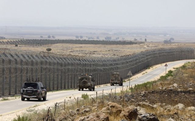 IDF vehicles driving along the road parallel to the border fence separating the Israeli and Syrian regions of the Golan Heights, July 19, 2017. (AFP/MENAHEM KAHANA)