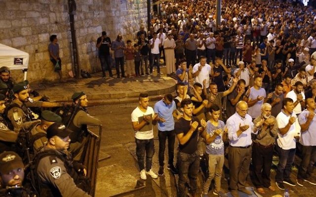 Israeli security forces stand by as Palestinian Muslim worshippers pray outside Lions' Gate, near a main entrance to the Temple Mount in Jerusalem's Old City, on July 24, 2017. (AFP/ Ahmad GHARABLI)