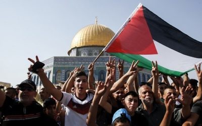 Worshipers wave a Palestinian flag and flash the victory gesture in front of the Dome of the Rock on the Temple Mount on July 27, 2017. (AFP Photo/Ahmad Gharabli)