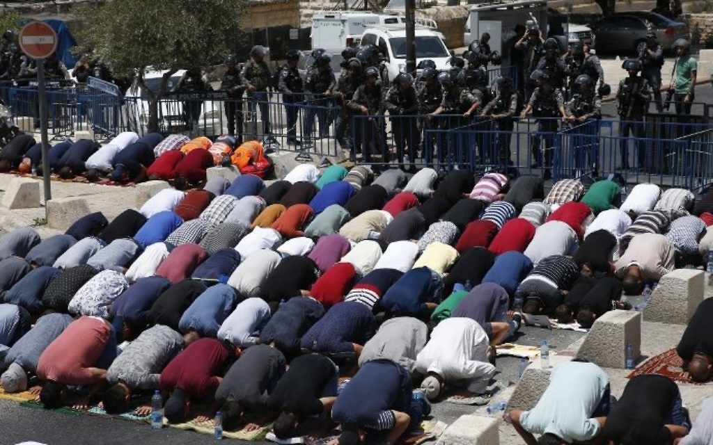 Israeli border guards keep watch as Palestinian Muslim worshipers pray outside Jerusalem's Old City overlooking the Temple Mount compound on July 28, 2017. (AFP PHOTO / AHMAD GHARABLI)
