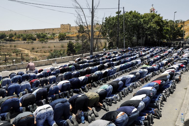 Muslim worshipers pray outside Jerusalem's Old City near the Lions' Gate on July 28, 2017. (AFP PHOTO / MENAHEM KAHANA)