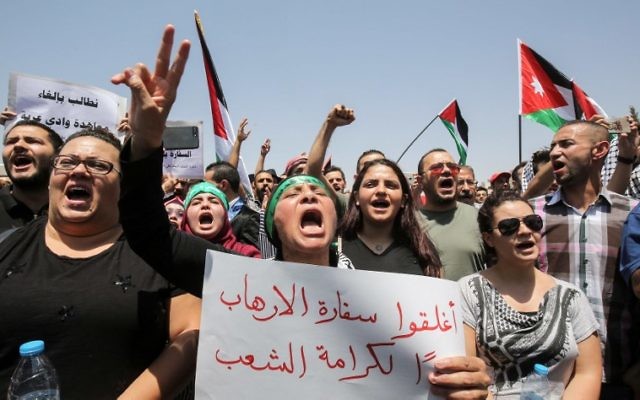 Jordanian protesters wave national flags and chant slogans during a demonstration near the Israeli embassy in the capital Amman on July 28, 2017, calling for the shutting down the of the embassy, expelling the ambassador, and canceling the 1994 peace treaty with Israel. (AFP PHOTO / KHALIL MAZRAAWI)