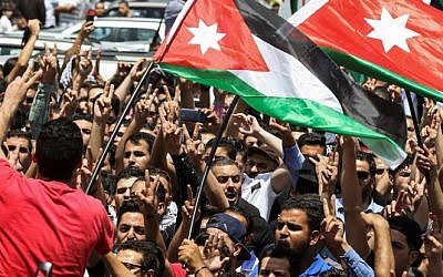 Jordanian protesters wave national flags and chant slogans during a demonstration near the Israeli embassy in the capital Amman on July 28, 2017, calling for shutting the embassy, expelling the ambassador, and canceling the 1994 peace treaty with Israel. (AFP Photo/Khalil Mazraawi)