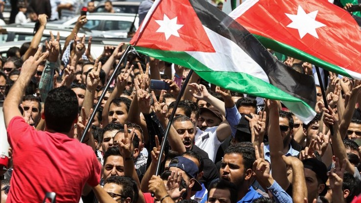 Jordanian protesters wave national flags and chant slogans during a demonstration near the Israeli embassy in the capital Amman on July 28, 2017, calling for the shutting down the of the embassy, expelling the ambassador, and canceling the 1994 peace treaty with Israel. (AFP PHOTO / KHALIL MAZRAAWI)