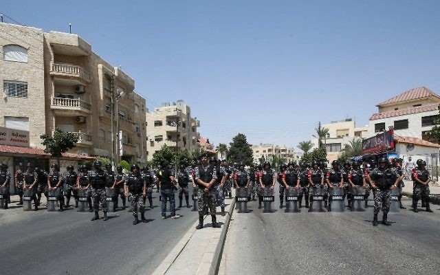 Jordanian security forces stand on guard in front of protesters during a demonstration near the Israeli embassy in the capital Amman on July 28, 2017, calling for the shutting down of the embassy, expelling the ambassador, and canceling the 1994 peace treaty with Israel. (AFP PHOTO / KHALIL MAZRAAWI)