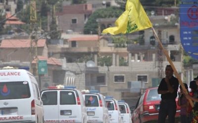 People wave a flag of the Lebanese Shiite Hezbollah movement as the group's ambulance convoy drives past, carrying bodies of fighters killed in week-long clashes in the Jurud Arsal border region, as part of a ceasefire deal. (AFP/Stringer)