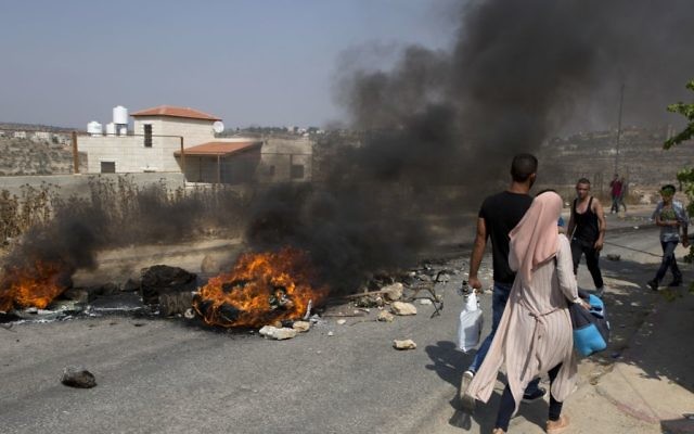 Palestinian protesters burn tires and clash with Israeli soldiers after troops searched and measured family house of Omar al-Abed, 20, perpetrator of Friday’s attack at the West Bank settlement of Halamish, in preparation for demolition, in the West Bank village of Kobar, near Ramallah, Saturday, July 22, 2017. (AP Photo/Nasser Nasser)