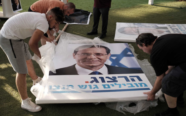 Workers holding large campaign posters during a rally supporting Labor party leader Isaac Herzog in Tel Aviv on June 26, 2017, (Tomer Neuberg/Flash90)