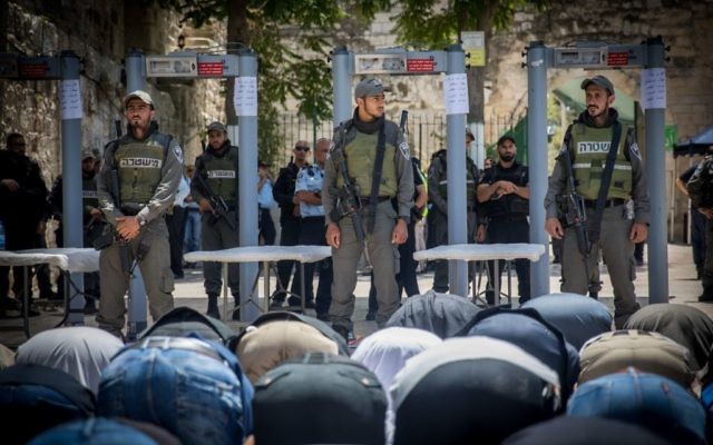 Muslims pray in front of metal detectors placed outside the Temple Mount, in Jerusalem's Old City, July 16, 2017. (Yonatan Sindel/Flash90)