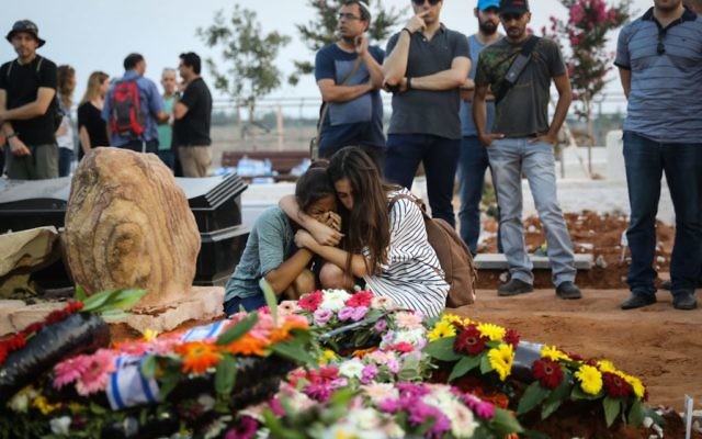 Friends and relatives mourn at the graves of Yosef Salomon, 70, his daughter Haya, 46, and son Elad, 36, after their funeral, attended by thousands, at the Modi'in Cemetery, on July 23, 2017.  (Yonatan Sindel/ FLASH90)