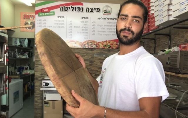Shlomi Madar with the wooden pizza pie tray similar to the one he used to fend off a Palestinian terrorist who tried to stab him in his pizza kiosk in Petah Tikva, July 24, 2017. (Jacob Magid)