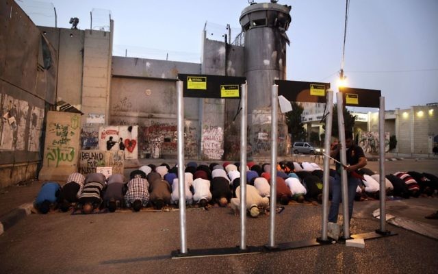 Palestinians pray in front of mock metal detectors during a demonstration in Bethlehem, Sunday, July 23, 2017. (AP Photo/Mahmoud Illean)