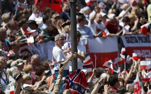 People climb a pole as others wave flags waiting for US President Donald Trump to deliver a speech in the city's Krasinski Square, in Warsaw, Poland, Thursday, July 6, 2017.(AP/Petr David Josek)