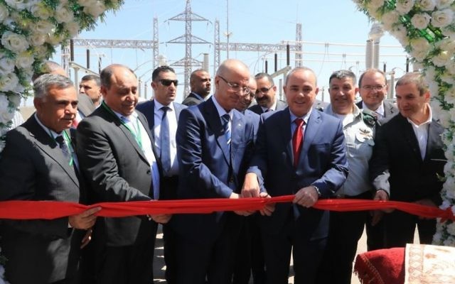 Israel's National Infrastructure Minister Yuval Steinitz (wearing red tie) and Palestinian Authority Prime Minister Rami Hamdallah cut the ribbon to mark the first ever commercial agreement between the Israeli and Palestinian energy companies to increase provision in the West Bank area of Jenin, July 10, 2017. Yoav Mordechai, Coordinator of Government Activities in the Territories, stands behind Steinitz,
 with Yiftach Ron Tal, Israel Electric Corporation head, on the far right.(Yossi Weiss).