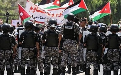 Jordanian security forces stand on guard as protesters wave Jordanian flags and chant slogans during a demonstration near the Israeli embassy in the capital Amman on July 28, 2017. (AFP Photo/Khalil Mazraawi)