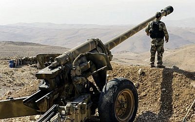 A tour guided by the Lebanese Shiite Hezbollah terror group shows one of the group's fighters standing next to an artillery gun in a mountainous area around the Syrian town of Flita near the border with Lebanon, August 2, 2017. (AFP PHOTO / LOUAI BESHARA)