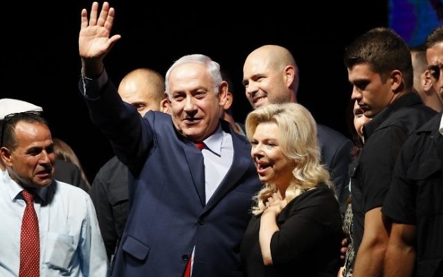 Prime Minister Benjamin Netanyahu, center, and his wife Sara, center-right, react during a gathering by Likud party members and activists to show support for them as they face corruption investigations, held at the Tel Aviv Convention Center, August 9, 2017. (AFP/Jack GUEZ)