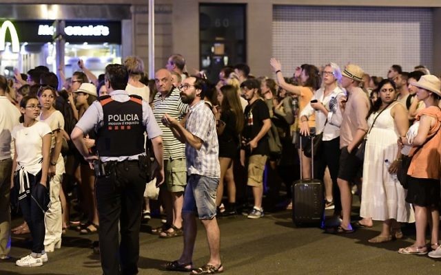 Tourists wait for the police to allow them to come back to their hotel on the Las Ramblas boulevard after a van plowed into the crowd, killing at least 13 people and injuring around 100 others in Barcelona, on August 18, 2017. (AFP/JAVIER SORIANO)